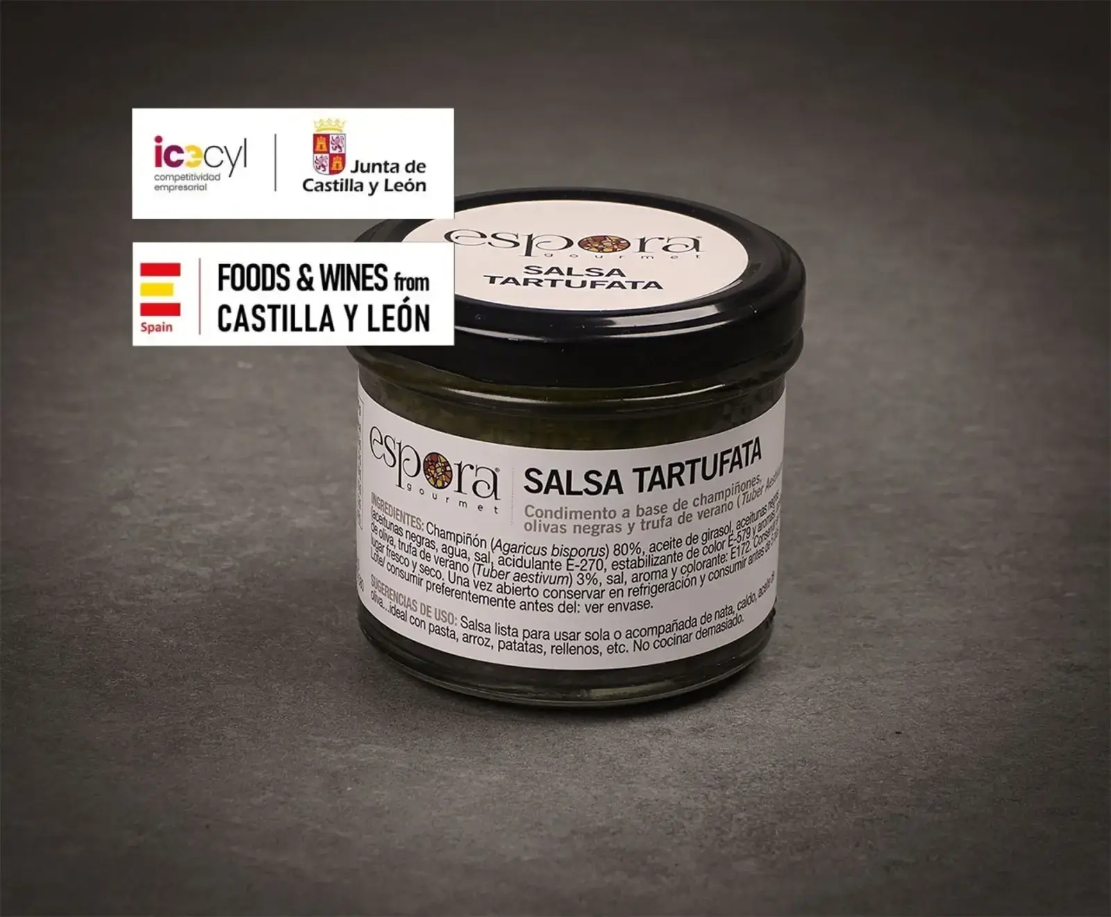 Ein Glas Espora Gourmet Salsa Tartufata (Trüffelsauce) mit schwarzem Deckel und weißem Etikett steht auf dunklem Untergrund. Im Hintergrund sind Logos von "Junta de Castilla y León" und "Foods & Wines from Castilla y León" zu sehen.