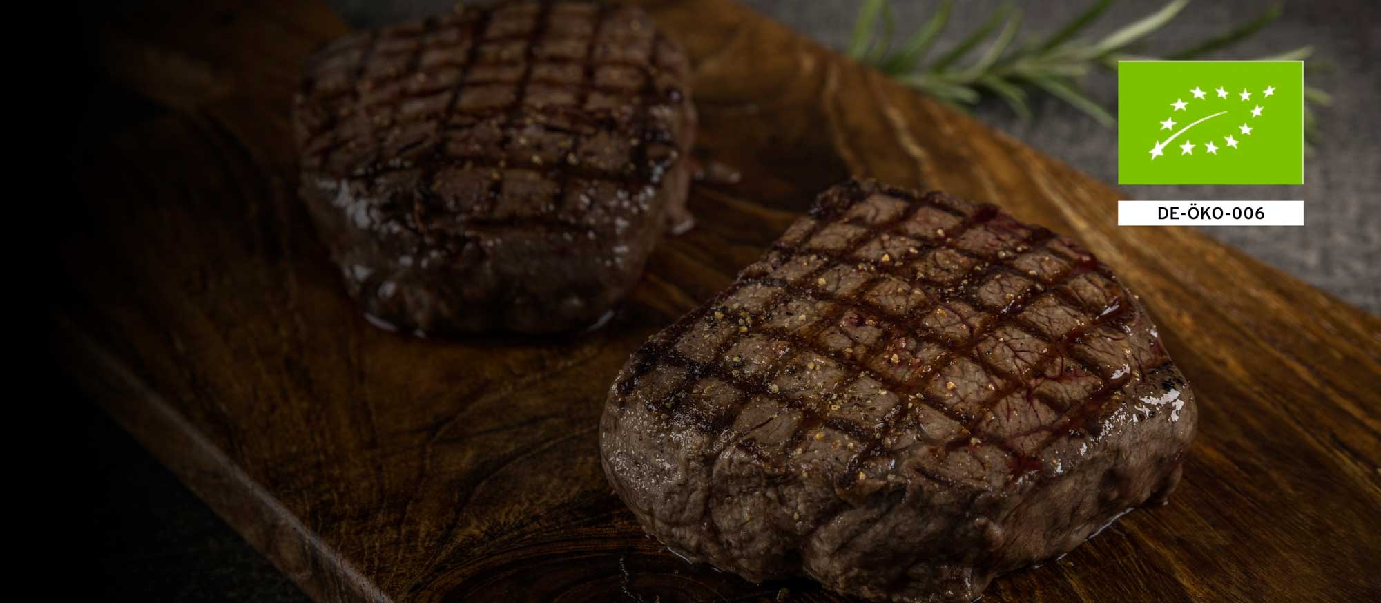 Zwei gegrillte Rindersteaks auf einem Holzbrett, servierbereit