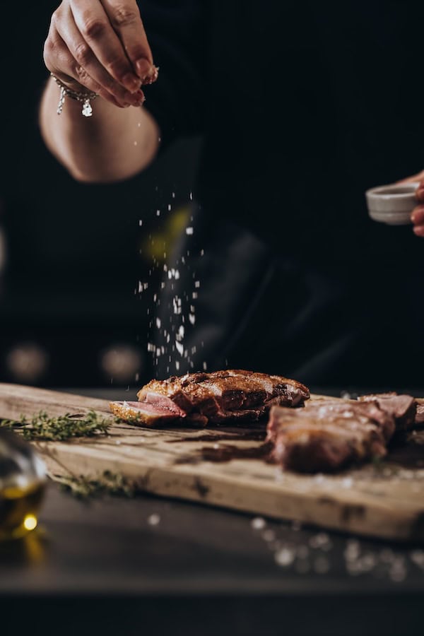 Mit Salz die fertig zubereitete gebratene Barbarie Entenbrust verfeinern