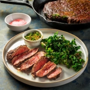 Saftiges Dry Aged Rumpsteak mit knusprigen Grünkohlchips auf einem Teller angerichtet