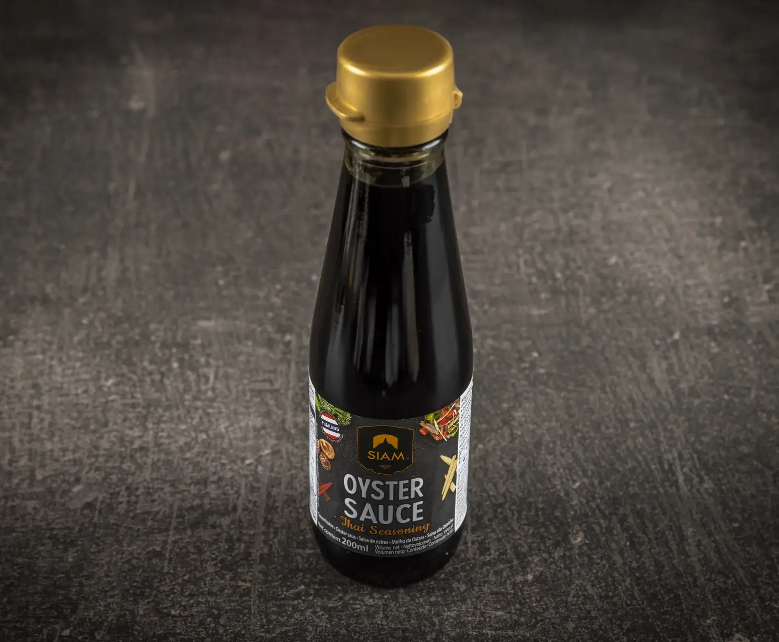 Eine aufrecht stehende, dunkle Flasche SIAM. Austernsauce Thai Seasoning mit goldenem Deckel und schwarzem Etikett, das den Inhalt von 200ml zeigt, auf dunklem, strukturiertem Hintergrund.