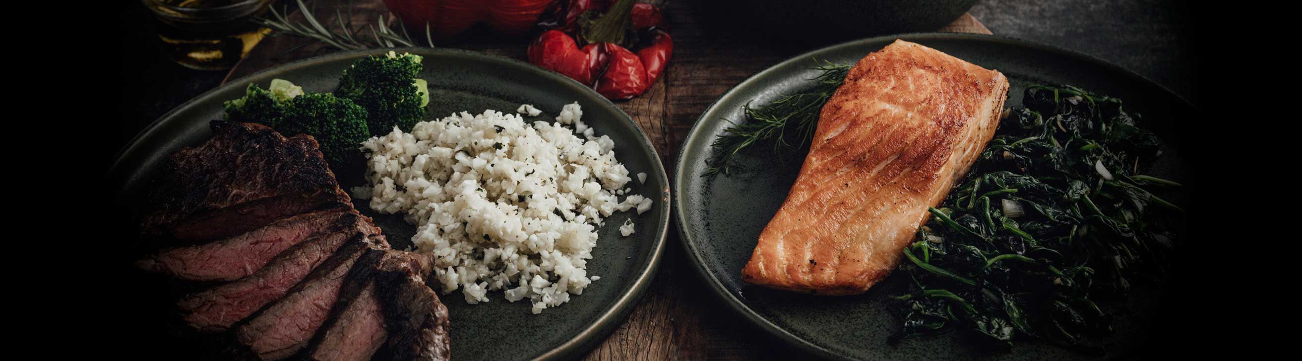 Norwegisches Lachfilet und Irisches Rumpsteak  mit Beilagen dekorativ auf zwei Tellern angerichtet