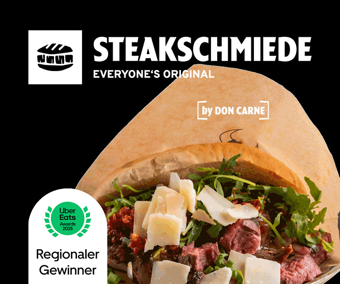 Ein Steak-Sandwich von "Steakschmiede by Don Carne" mit Rucola und Parmesan, in Papier gewickelt. Unten links ein "Uber Eats Awards 2025 Regionaler Gewinner"-Abzeichen.