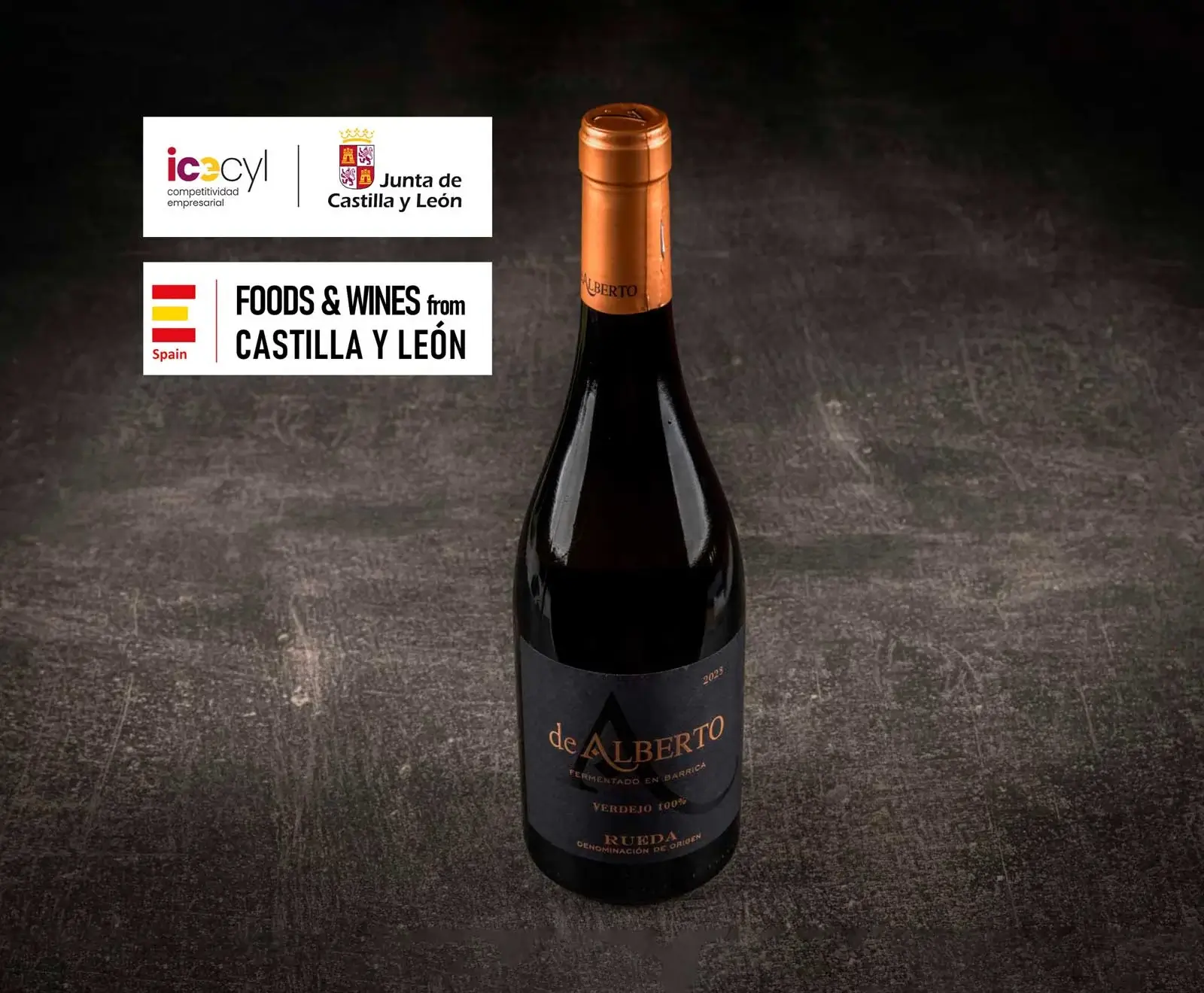 Eine Flasche de Alberto Verdejo 100% Wein aus Rueda, Jahrgang 2023, mit schwarzem Etikett und kupferfarbener Kapsel auf dunklem Untergrund. Oben links sind Logos von Castilla y León.