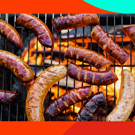 Verschiedene Würste, darunter helle und dunkle Sorten, brutzeln auf einem Grillrost über lodernden Flammen. Die Würste zeigen deutliche Grillspuren und sind appetitlich gebräunt.
